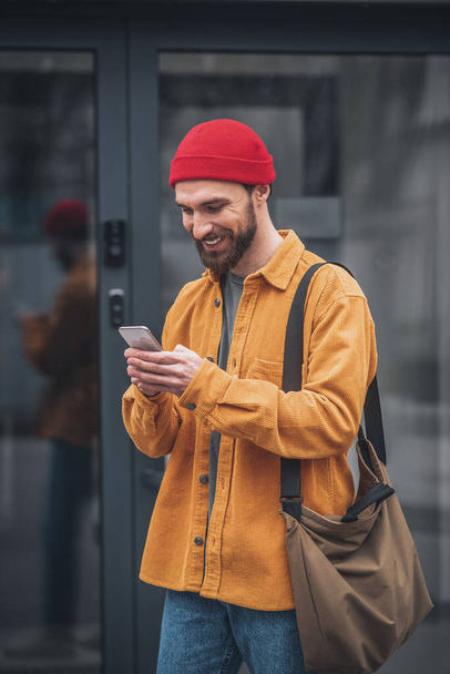 Man in an orange jacket with a phone in his hands - Φωτογραφία, εικόνα