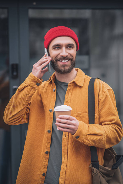 Man in an orange jacket with a phone in his hands - Foto, immagini