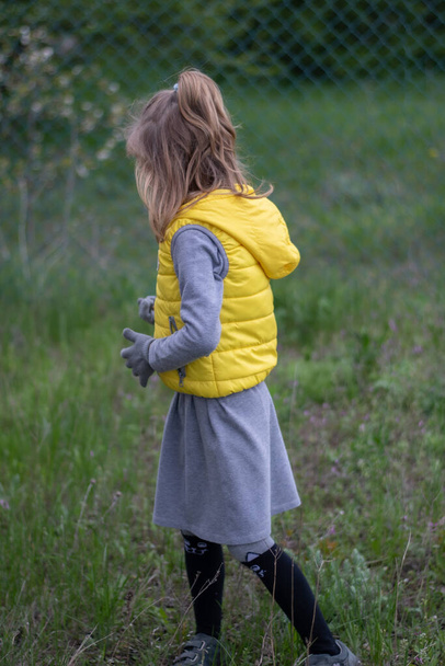 Pieni tyttö trendikkäissä väreissä vaatteet - keltainen liivi ja harmaa mekko - Valokuva, kuva