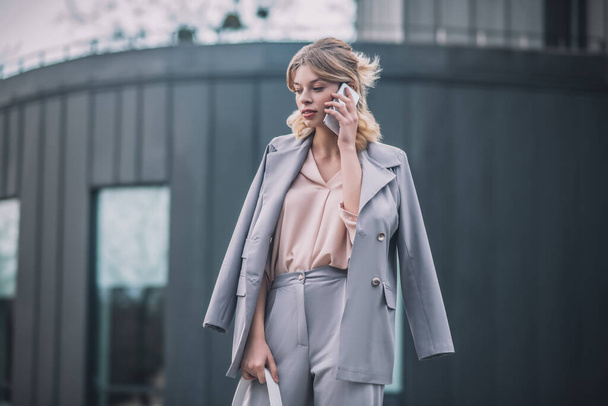 Woman in business suit with smartphone near ear - Foto, imagen
