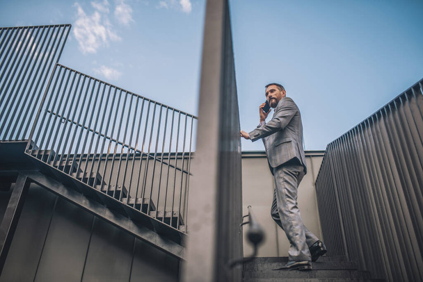 Man with smartphone climbing stairs outdoors - Fotó, kép