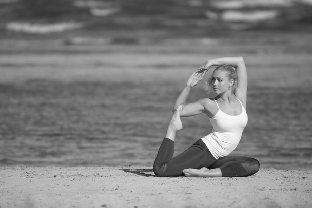 Mujer yoga en ropa deportiva relajante por mar - Foto, imagen