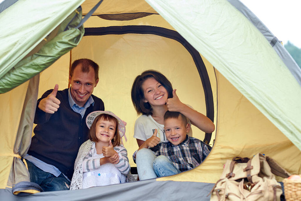 Family Parents and two children in camp tent. Happy Mother, father, son and daughter on Summer vacation. - Foto, Imagen