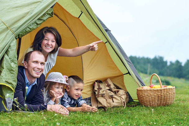 Aile ve iki çocuk kamp çadırında. Mutlu anne, baba, oğul ve kız yaz tatili. - Fotoğraf, Görsel