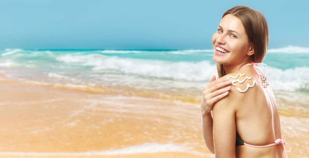 Beautiful young woman applying sun protection cream at sea resort - Foto, immagini