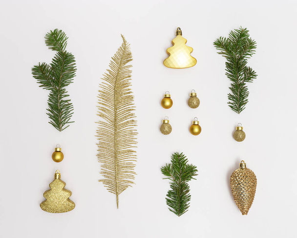 Christmas composition with golden christmas decor, green fir branches, balls,  palm leaf, shine pine cone, glitter fir tree on white background. New Year holiday decoration. Flat lay, top view. - Foto, immagini
