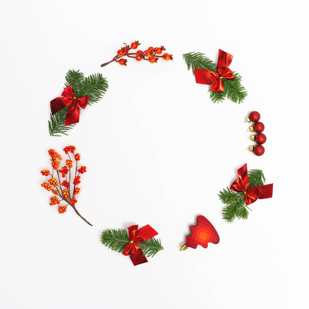 Christmas round frame from natural green fir branches and small red glitter balls and berries on white background. New Year winter holiday concept. Flat lay, top view. - Valokuva, kuva