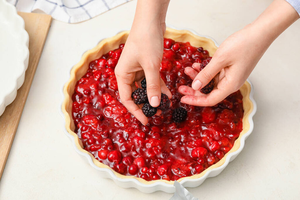 Woman cooking berry pie in kitchen - 写真・画像