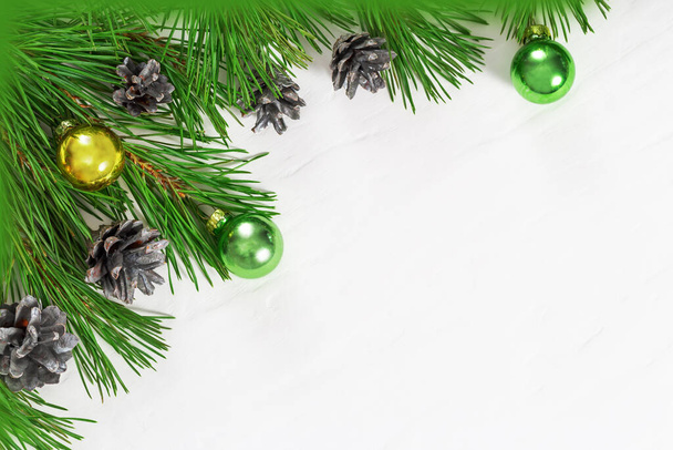 Moldura de Natal de ramos de árvore de Natal, pequenos cones e bolas de vidro no fundo leve com espaço de cópia. Conceito de Ano Novo - Foto, Imagem
