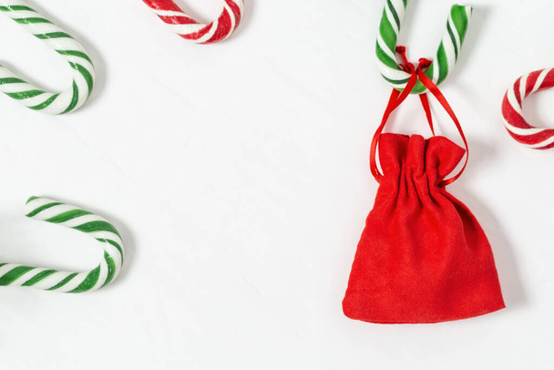Christmas background with candy canes and gift in small red bag. Christmas composition. Top view, copy space. - Valokuva, kuva