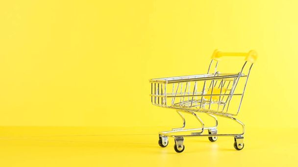 empty Shopping cart on a yellow background, closeup. Black Friday Shopping and Discount Concept - Foto, Imagen