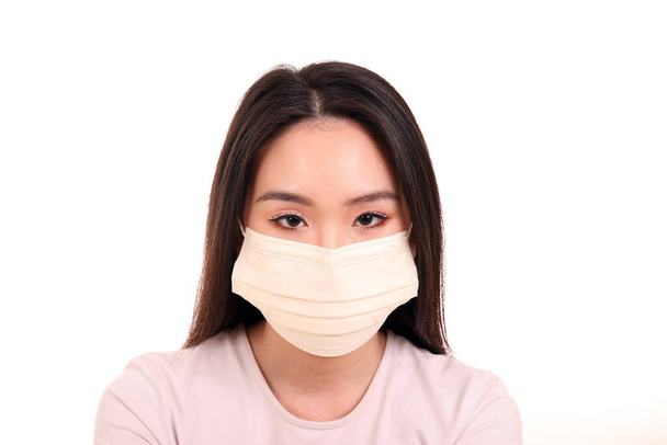 Молода жінка з Південно - Східної Азії, одягнена в жовтий колір з білої шкіри, має три радикальні противірусні хірургічні маски на білому тлі. - Фото, зображення