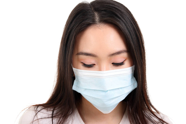 Красивая молодая юго-восточная азиатка в синей трехслойной антивирусной хирургической маске на белом фоне - Фото, изображение