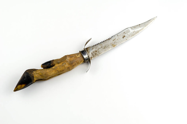 Ένα παλιό κυνηγετικό μαχαίρι φτιαγμένο από οπλή κατσίκας στο λευκό φόντο. Μαχαίρι με πριόνι και χειροφυλακτήρα. Κρύα όπλα. - Φωτογραφία, εικόνα