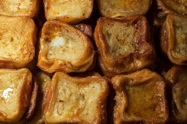 Свежеприготовленные торрихас, типичный испанский сладкий жареный тост из нарезанного хлеба, пропитанного яйцами и вином. Традиционный десерт Страстной недели в Испании. - Фото, изображение