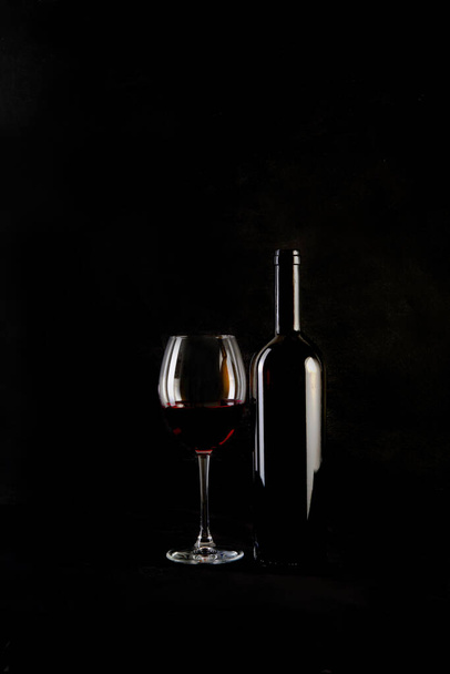 Garrafa de vinho tinto com 2 copos e abridor de garrafas em fundo preto. Espaço de cópia - Foto, Imagem