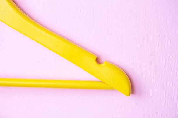 One wooden yellow clothes hanger on a bright pink background. Creative flat lay with copy space. Shopping concept - Photo, Image