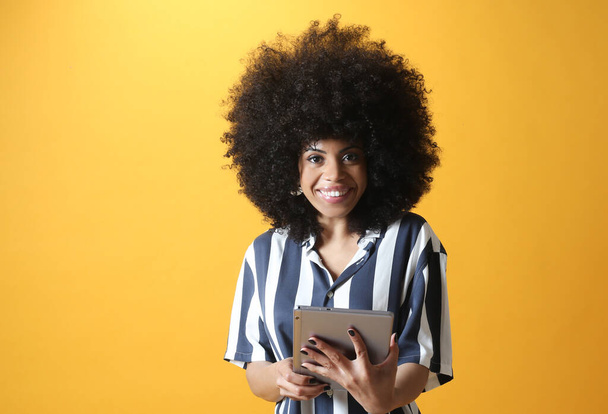 Афро-женщина улыбается, держа планшет - Фото, изображение