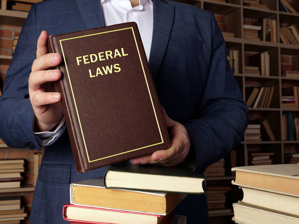 Juriste détient le livre FEDERAL LAWS. Le droit fédéral est l'ensemble des lois créées par le gouvernement fédéral d'un pays. - Photo, image