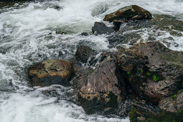 Nagy kövek mohával és zuzmóval a hegyi folyó vizében. A hegyi patak hatalmas vízfolyása. Természetes texturált gyors háttér gyors áramlását hegyi patak. Mossy sziklák közelkép. - Fotó, kép