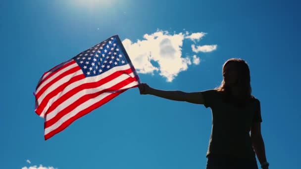 Γυναίκα κρατά σημαία ΗΠΑ κατά του μπλε ουρανού - Πλάνα, βίντεο