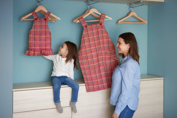 Mother and daughter with similar clothes at home - Photo, Image
