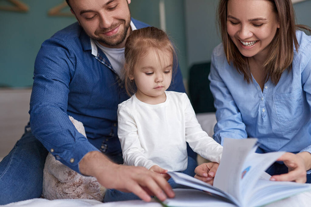 Family reading book together at home - Zdjęcie, obraz