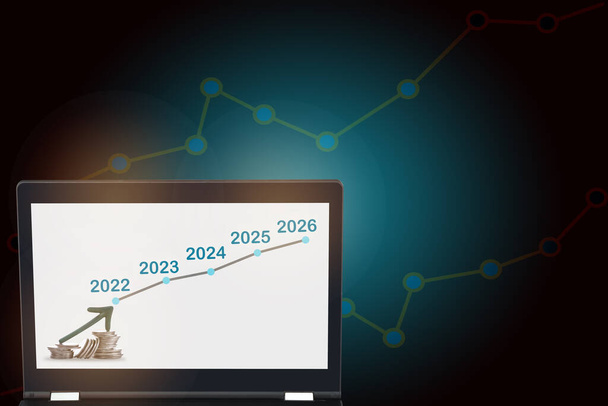Strzałka w górę na stosie monet i wykres wzrostu 2022 do 2026 na laptopie. Zwrot z inwestycji ROI koncepcji i zarabianie pieniędzy z oszczędności pomysł. Wzrost i rynek byków - Zdjęcie, obraz