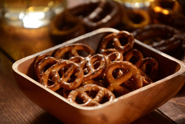 Hard Pretzels or Salted pretzels snack for party on rustic wooden table with glass of beer - Фото, изображение