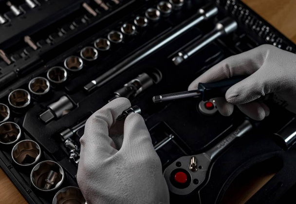 Male hands in gloves over open toolbox with different metal tools for car and home repair, close up - Foto, Imagen