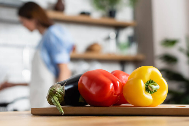 крупный план свежих цельных овощей на разделочной доске на кухне - Фото, изображение