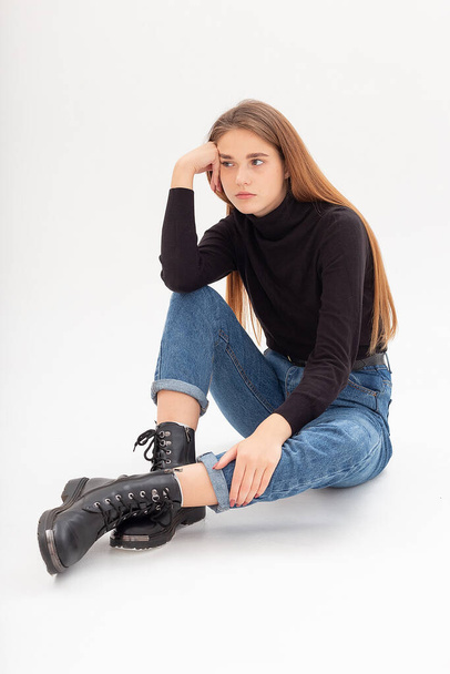 young attractive caucasian woman in black turtleneck, blue jeans at white studio - Fotó, kép