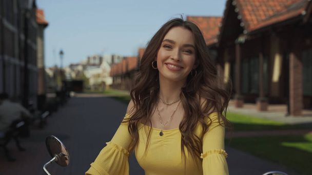 happy young woman with wavy hair smiling outside - Φωτογραφία, εικόνα