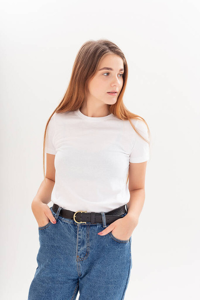young caucasian pretty girl with long hair in t-shirt, blue jeans at studio - Photo, Image