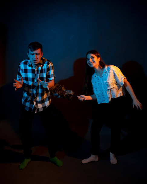 A guy in a plaid shirt and a girl with a dust brush against a dark background - Fotoğraf, Görsel
