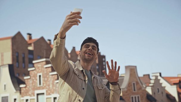 happy man waving hand while having video call on smartphone  - Φωτογραφία, εικόνα