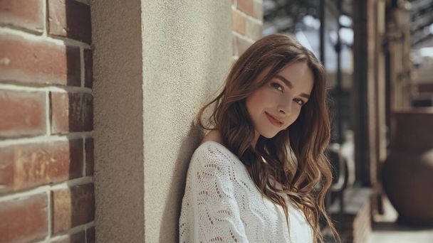 smiling young woman looking at camera near building outside - Фото, зображення
