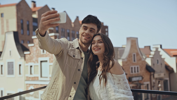alegre hombre tomando selfie con feliz mujer fuera  - Foto, Imagen