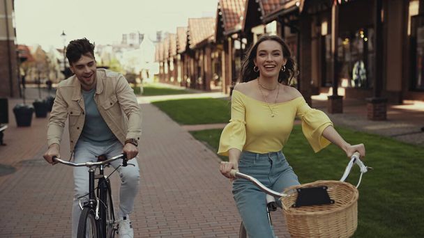positive woman and man riding bicycles on street  - Φωτογραφία, εικόνα