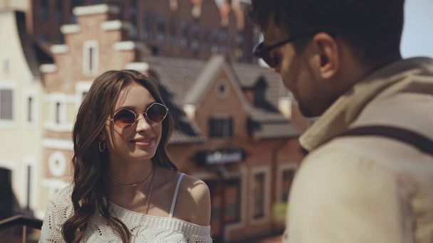 happy woman in sunglasses looking at blurred man  - 写真・画像