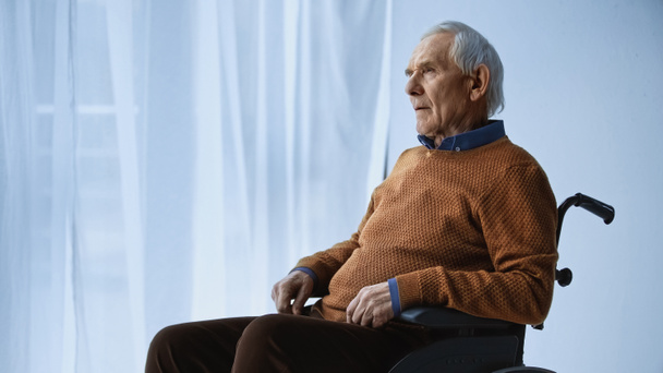 dreamy senior man in wheelchair sitting at retirement home - Фото, изображение