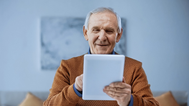 現代のリビングルームでタブレットを使って笑顔の老人が - 写真・画像