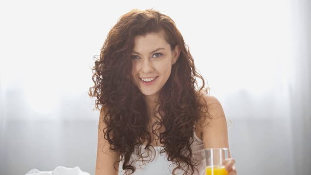 szczęśliwa młoda kobieta trzyma szklankę soku pomarańczowego rano  - Zdjęcie, obraz