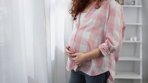 vista ritagliata della giovane donna incinta che tocca la pancia - Foto, immagini