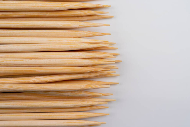 Multiple wooden bamboo skewers laying on white background in a row, use for background, Close view of the pointed ends of skewer sticks macro view - Fotó, kép