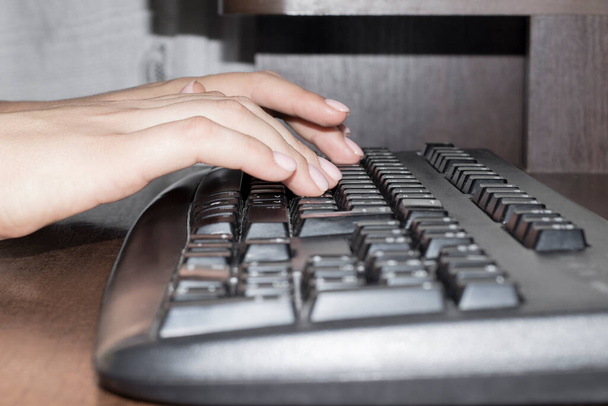 Τα γυναικεία χέρια πληκτρολογούν κείμενο σε μαύρο πληκτρολόγιο - Φωτογραφία, εικόνα