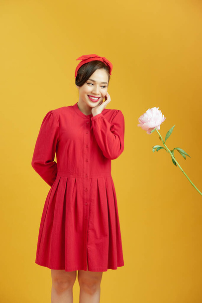 Man giving pink peony flowers and shy woman isolated on yellow background - Foto, Imagem