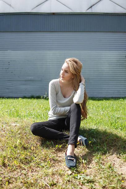 kaukázusi fiatal sovány nő barna haj ül zöld gyep a falon - Fotó, kép