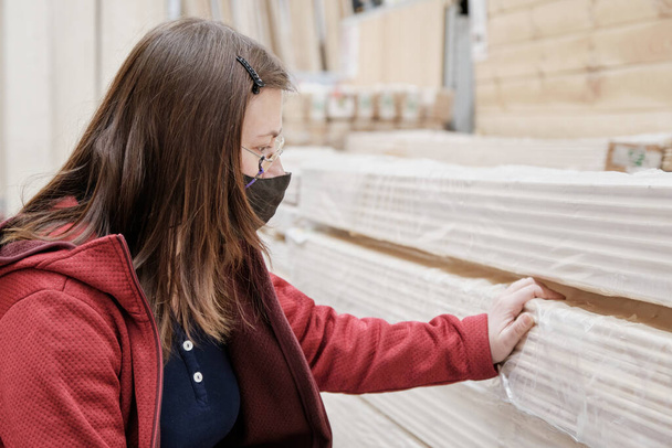 Woman in building materials store chooses long wooden slats to buy. Close up - Foto, Imagen