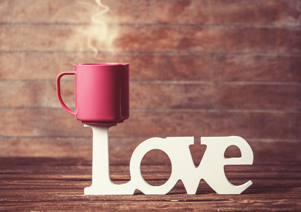 Tee- tai kahvikuppi sanalla Rakkaus puupöydällä
. - Valokuva, kuva